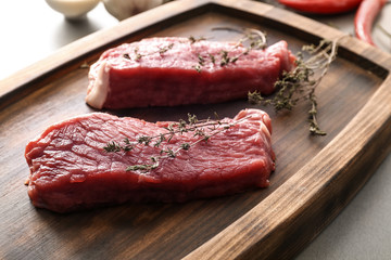 Fresh raw meat with thyme on wooden tray