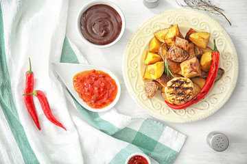 Bowls of barbecue and chili sauce with grilled potato on table
