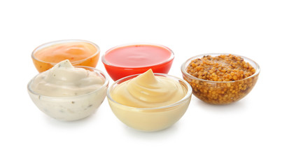 Bowls with different sauces on white background