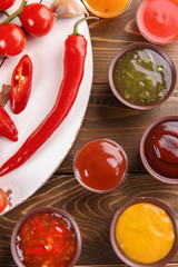Flat lay composition with different sauces and ingredients on wooden background