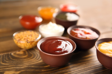 Bowls with different sauces on wooden background