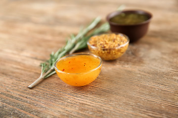 Bowls with different sauces and rosemary on wooden background