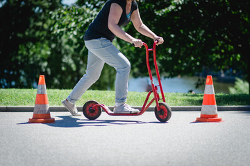 Man or woman riding a course with a scooter between two obstacles