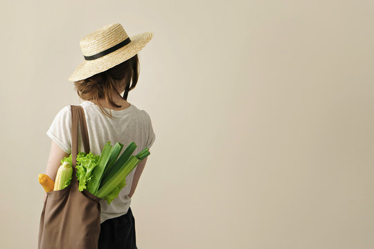 young woman holding textile grocery bag with vegetables