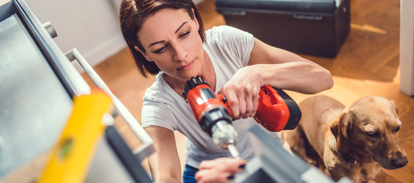 Woman with dog building kitchen and using a cordless drill