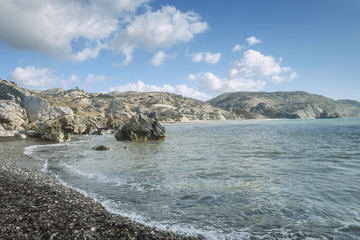 Naklejka premium fragment of the stony beach of Aphrodite against the background of mountains and blue sky