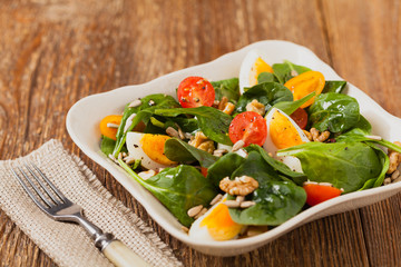 Delicious salad of fresh spinach, boiled egg, tomatoes, nuts and sunflower seeds