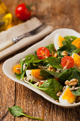 Delicious salad of fresh spinach, boiled egg, tomatoes, nuts and sunflower seeds