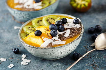Fruit smoothie with blueberries, coconut flakes and chia seeds in bowl. Selective focus.