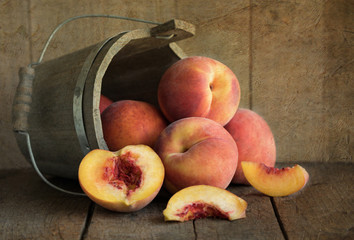 Rustic type photograph of fresh yellow peaches flowing out of a wooden bucket