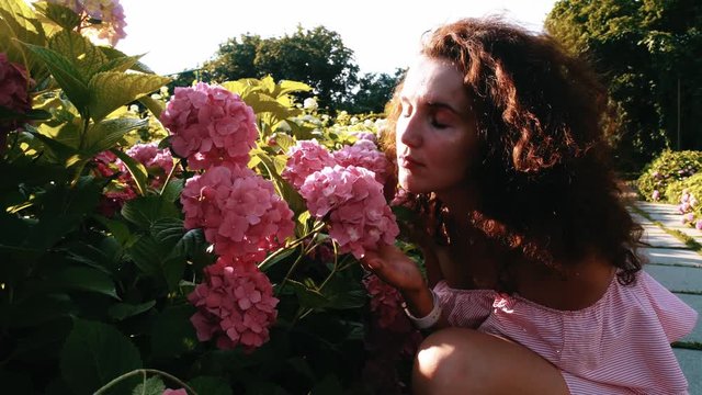 Young pretty woman smelling flowers in the garden
