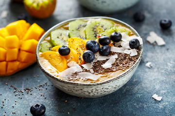 Healthy Mango Smoothie with chia seeds, coconut flakes, kiwi and blueberries.