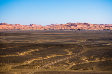 Fototapeta na wymiar Volcanic black basalt terrain in Sahara desert in Morocco