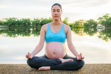 Fototapeta na wymiar Pregnancy exercise. Prenatal yoga. Pregnant woman doing yoga beside the lake. Relaxing moment.