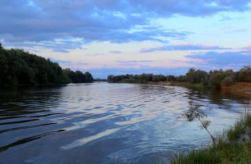 Beautiful summer landscape of the river in the Volga Delta. Clouds at sunset. Astrakhan Region. Wild nature of Russia.