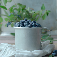 Honeysuckle berry in metal cup with green leaves on a wooden table