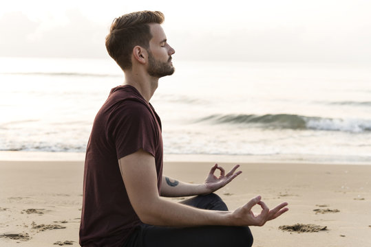 Man practicing yoga on the beach