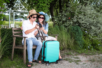 Plakat couple traveler have a baggage sitting on the chair and taking photo view of nature during go to trip on vacation.