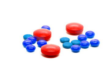 Red tablets and colored pills scattered on the table. A concept with an emphasis on red pills. Isolated on white background. For design in pharmacology, pharmacy, dietary supplements, drugs.