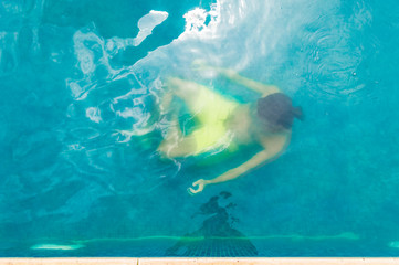 Top view of a young man floating underwater in swimming pool