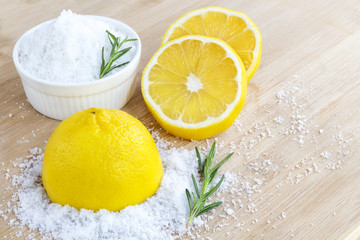 Lemon and sea salt - Beauty treatment with organic cosmetics with lemon ingredients on wood and rosemary background for body scrub and spa care.