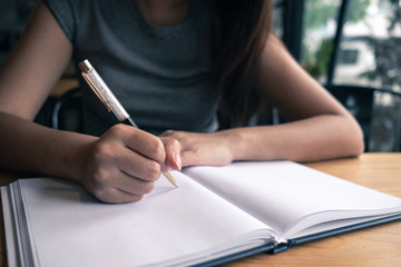 Woman writing down her idea on notebook in coffee shop