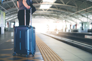 Woman with suitcase waiting for a train in modern station platform
