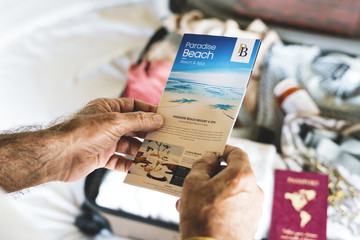 Man holding up beach travels brochure