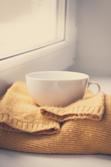 Details of still life in the home interior. Sweater, cup, wool, cozy, book, candle. Moody. Cosy autumn winter concept. Copy space