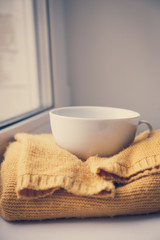 Details of still life in the home interior. Sweater, cup, wool, cozy, book, candle. Moody. Cosy autumn winter concept. Copy space