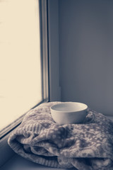 Details of still life in the home interior. Sweater, cup, wool, cozy, book, candle. Moody. Cosy autumn winter concept. Copy space
