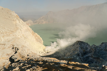Crater with acidic crater lake, Kawah Ijen the famous tourist attraction, where sulfur is mined. Extraction of sulfur in the crater of a volcano. Sulfur gas, smoke.