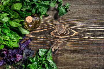 Fototapeta na wymiar Variety of fresh organic herbs on wooden background. Freshly harvested herbs including basil, arugula. Top view. Copy space.