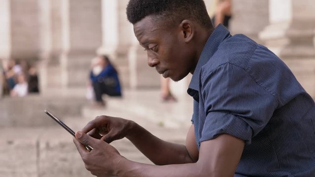 Attractive young african man usig tablet outdoor- profile