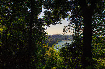 view of the lake of Albano among the branches of the trees, tourist area of the Roman castles, Rome Italy