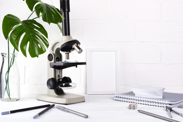 Biology education concept - Assortment of supplies,  microscope on white background Minimalistic school or office workspace