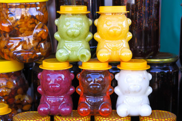 Colored honey in jars in the form of bears sold for children at the fair Souvenirs