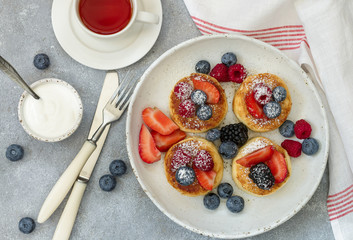 Cottage cheese pancakes, syrniki, curd fritters with fresh berries (raspberry, strawberry, blueberry, BlackBerry) and powdered sugar in a white plate