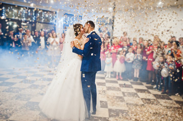 Gorgeous wedding couple performing their first dance with confetti, colorful lights and fireworks.