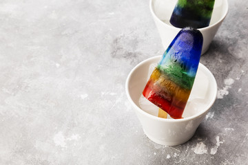 Rainbow ice cream popsicle on a gray background. Copy space. Food background