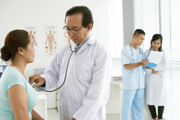 Doctor checking heartbeat of patient