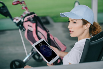 side view of pensive female golf player with tablet in hands at golf course