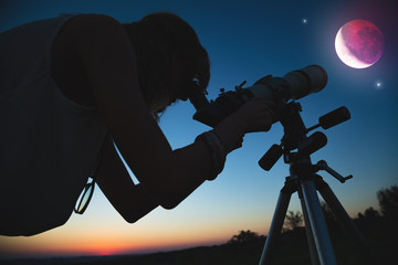 Girl looking at lunar eclipse through a telescope. My astronomy work.