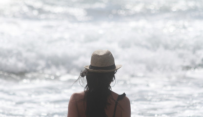 Beautiful girl, seen from behind, with hat who look the sea. Sea in the background. Sabaudia, Lazio, Italy