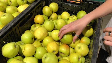 Young woman choosing apples in a supermarket picked from organic farm.