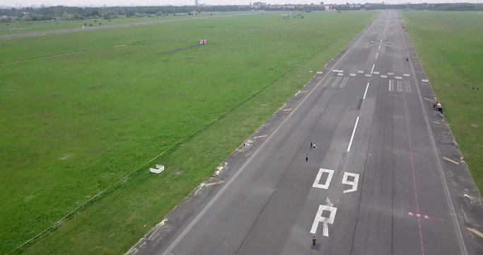 Revealing a runway with people on it at abandoned airport.