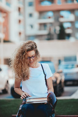 Female student sitting on bench and reading book.