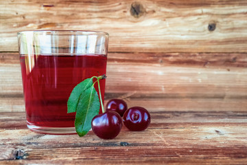 Cherry juice and cherry berries on wooden background