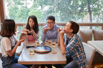 Friends eating pizza in cafe