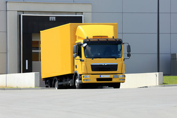 yellow truck at the warehouse gate - obrazy, fototapety, plakaty